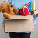 A person holding a box full with children's toys