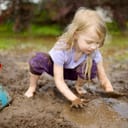Small girl playing in the mud