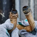 close-up of a rusty, corroded, bent plumbing pipes held by a plumber wearing work gloves