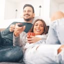Young couple happily watching TV together at home