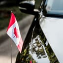 Selective focus on a Canadian flag on a black car