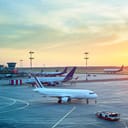 Numerous airplanes parked on the runway at an airport