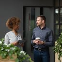 Young businesswoman chatting with a businessman as they walk through the office hallway.