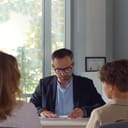 School official talking to a mother and her child in a school office