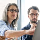 A middle aged woman showing something on a computer to her colleague