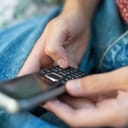 close-up of a person using an old push-button mobile phone