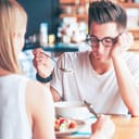 A bored man fiddling with his food at a restaurant