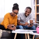A young couple sitting on a couch sorting out finances