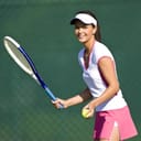A tennis played standing ready to serve against a green background.
