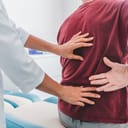 close-up of an orthopedist examining a patient's back for pain in a clinic