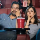 Young couple on a date looking bored while watching a movie in a cinema theater