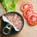 Ingredients for a tuna sandwich, including canned tuna, bread, lettuce, and tomato