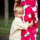 little shy boy holding the feet of parents. little boy hiding behind his mother's skirt outdoor.