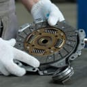 mechanic carrying out clutch replacement, inspecting the drive, driven disc, and pilot bearings during car repair