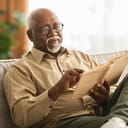 A senior man reading a book while sitting on a couch