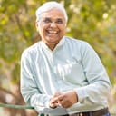 Smiling elderly man resting on a metal fence