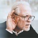 A older man having a hard time hearing and cupping his hand on their ear