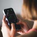 Young female investor holding a phone showing a stock market index growth chart on an investment app