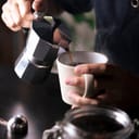Barista pouring coffee from a Moka pot into a cup