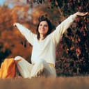 Happy Cheerful Woman Enjoying Autumn Sitting in the Park. Carefree lady de-stressing feeling healthy and optimistic
