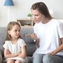 young mother scolding her little daughter in their living room