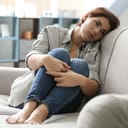 Depressed young woman sitting on sofa