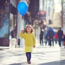 A little girl holding a blue balloon