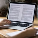close-up of a laptop screen showing a document, young woman working on her essay at home