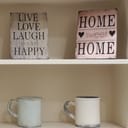 Decorative shelf with mugs and inspirational signs for home decoration