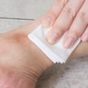 Close-up of a woman's hand compressing a gauze bandage onto a leg wound to stop the bleeding.