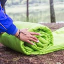 Woman rolling up a sleeping bag on the ground