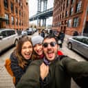 Three people taking a selfie under Manhattan bridge