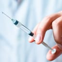 close-up of a hand holding a medical syringe with a needle, ready for vaccination or injection