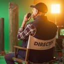 A movie director sitting in his chair talking into a walkie talkie