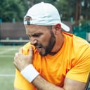 young man with a beard clutching his shoulder in pain