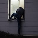 Burglar entering a house through an open window