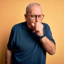 an older man coughing, isolated on an orange background