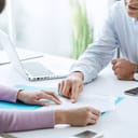 young woman in a business meeting with an executive who is pointing at a contract and explaining details