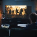 man watching a movie in his living room with popcorn in front of him on the table