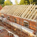Construction of a brick house with scaffolding around it.