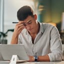 stressed young businessman at office desk with tablet in front of him