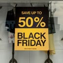 Black and yellow poster on a window of a shop saying 'Save up to 50% Black Friday deals'.