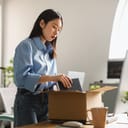 A young woman packing her stuff from an office into a cardboard box