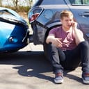 a guy making a phone call after a car accident