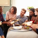 diverse group of friends gathered at home, engaged in a lively book club discussion