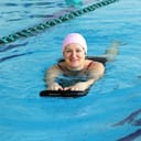 a middle aged woman learning how to swim in a swimming pool