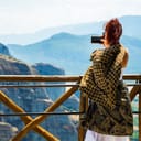 A female tourist capturing the breathtaking views of the cliffs and the town of Kalabaka, Meteora Monasteries, Greece.
