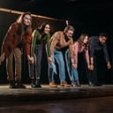 Actors holding hands on a stage and bowing to audience