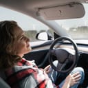 A woman driving a Tesla in an autonomous mode without controlling the vehicle