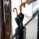 A person placing an umbrella in an umbrella stand